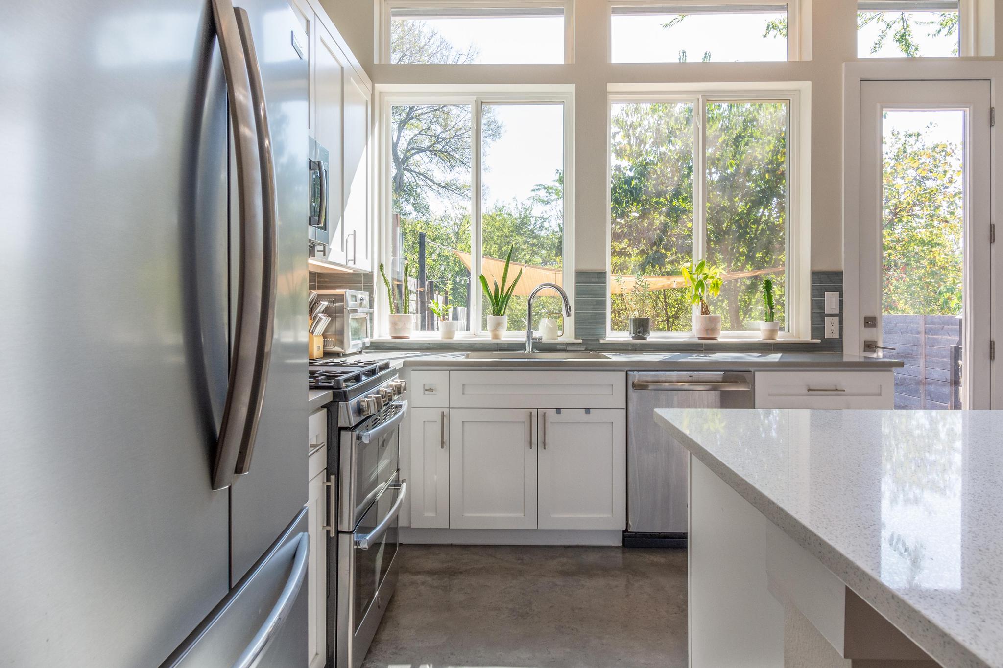 1177 Pandora Street, Unit B Austin, TX 78702 - Photo 6 of 30 Kitchen with stainless steel appliances, finished concrete floors, white cabinetry, and light stone countertops
