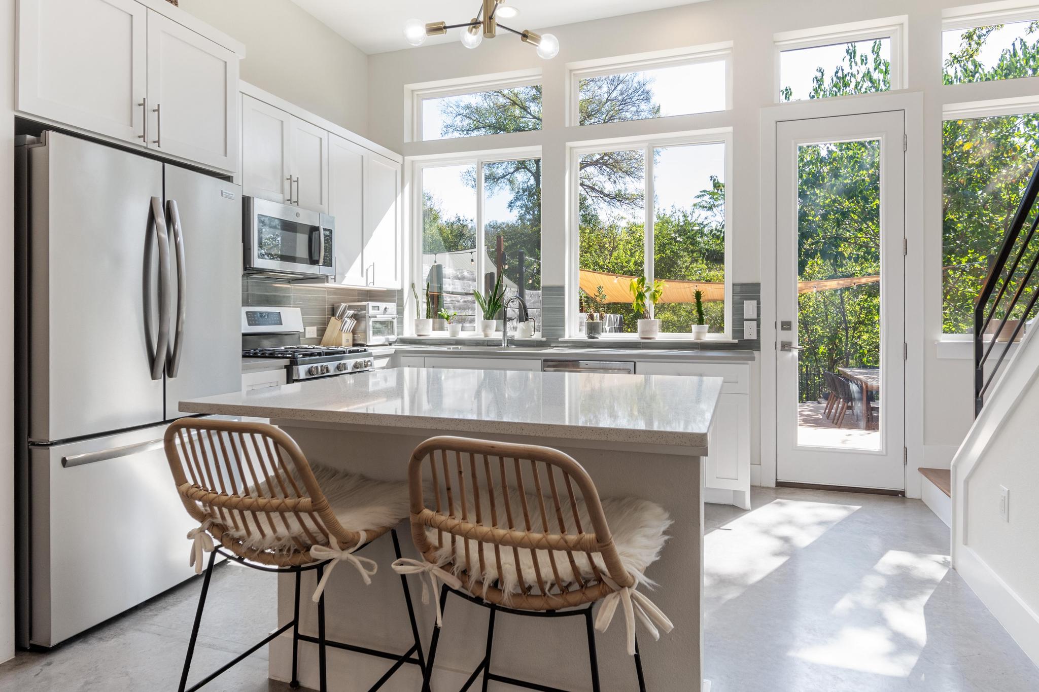 1177 Pandora Street, Unit B Austin, TX 78702 - Photo 7 of 30 Kitchen featuring white cabinetry, stainless steel appliances, concrete flooring, light stone countertops, and a breakfast bar area