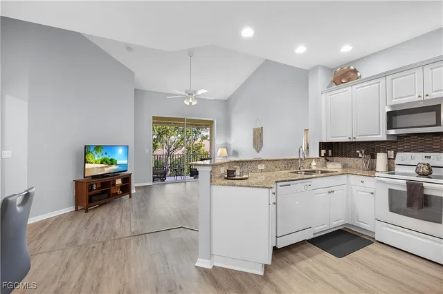 a kitchen with stainless steel appliances granite countertop a stove top oven a sink a dining table and chairs with wooden floor