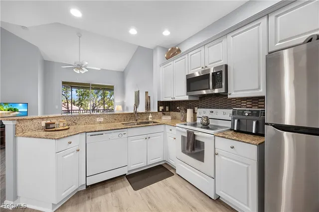 a kitchen with stainless steel appliances granite countertop a stove top oven a sink and a refrigerator