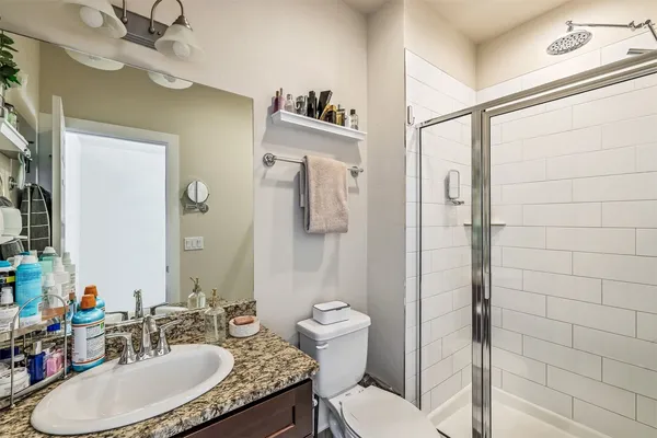 a bathroom with a granite countertop sink a toilet a mirror and shower