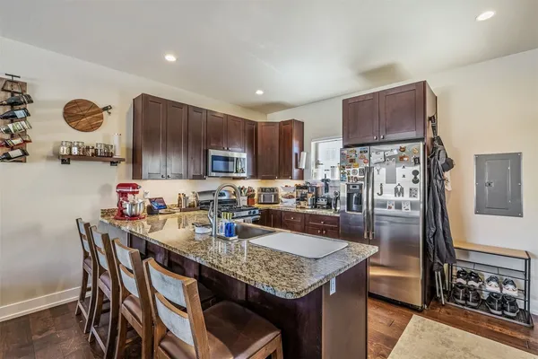 a kitchen with kitchen island granite countertop a sink cabinets and stainless steel appliances