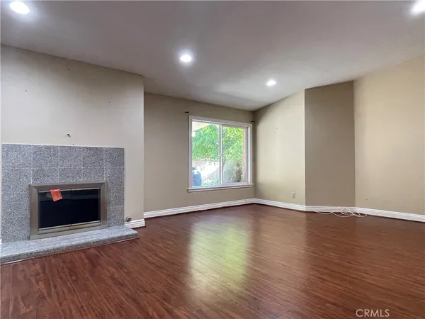 a view of an empty room with wooden floor fireplace and a window