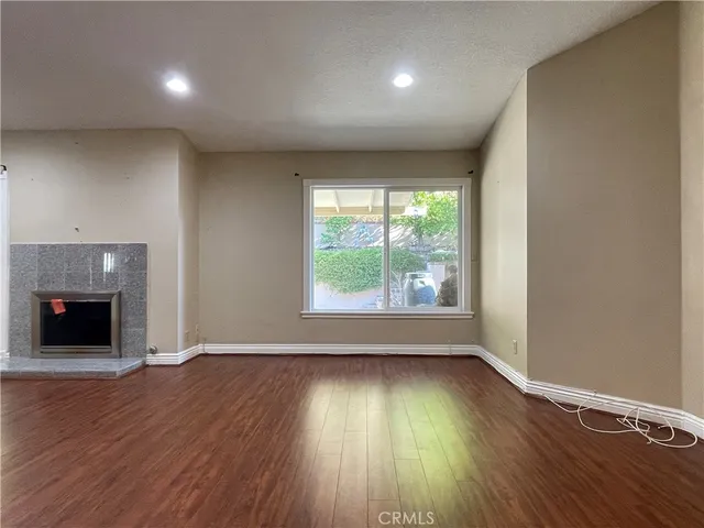 an empty room with wooden floor fireplace and windows
