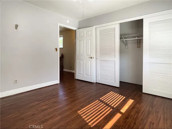 an empty room with wooden floor & closet area