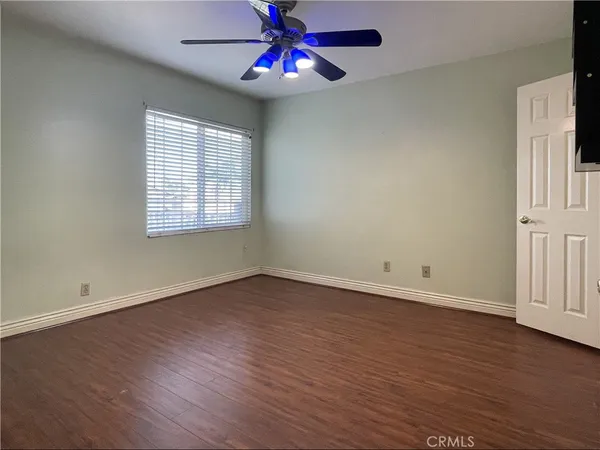 an empty room with wooden floor closet chandelier fan and windows