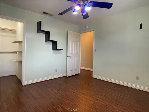 an empty room with wooden floor chandelier fan and windows