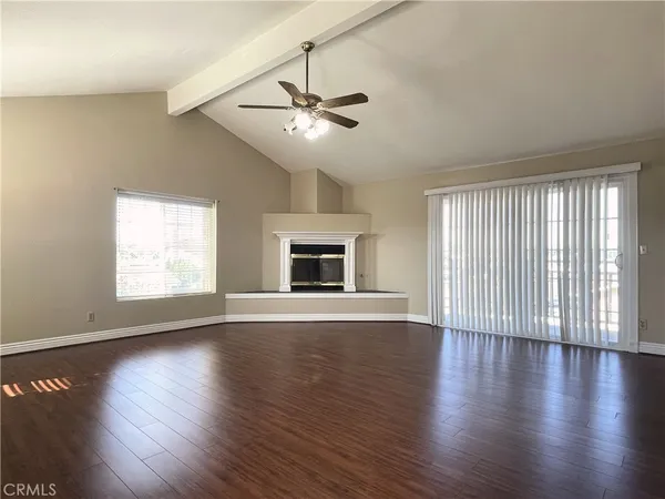 an empty room with wooden floor chandelier fan and windows