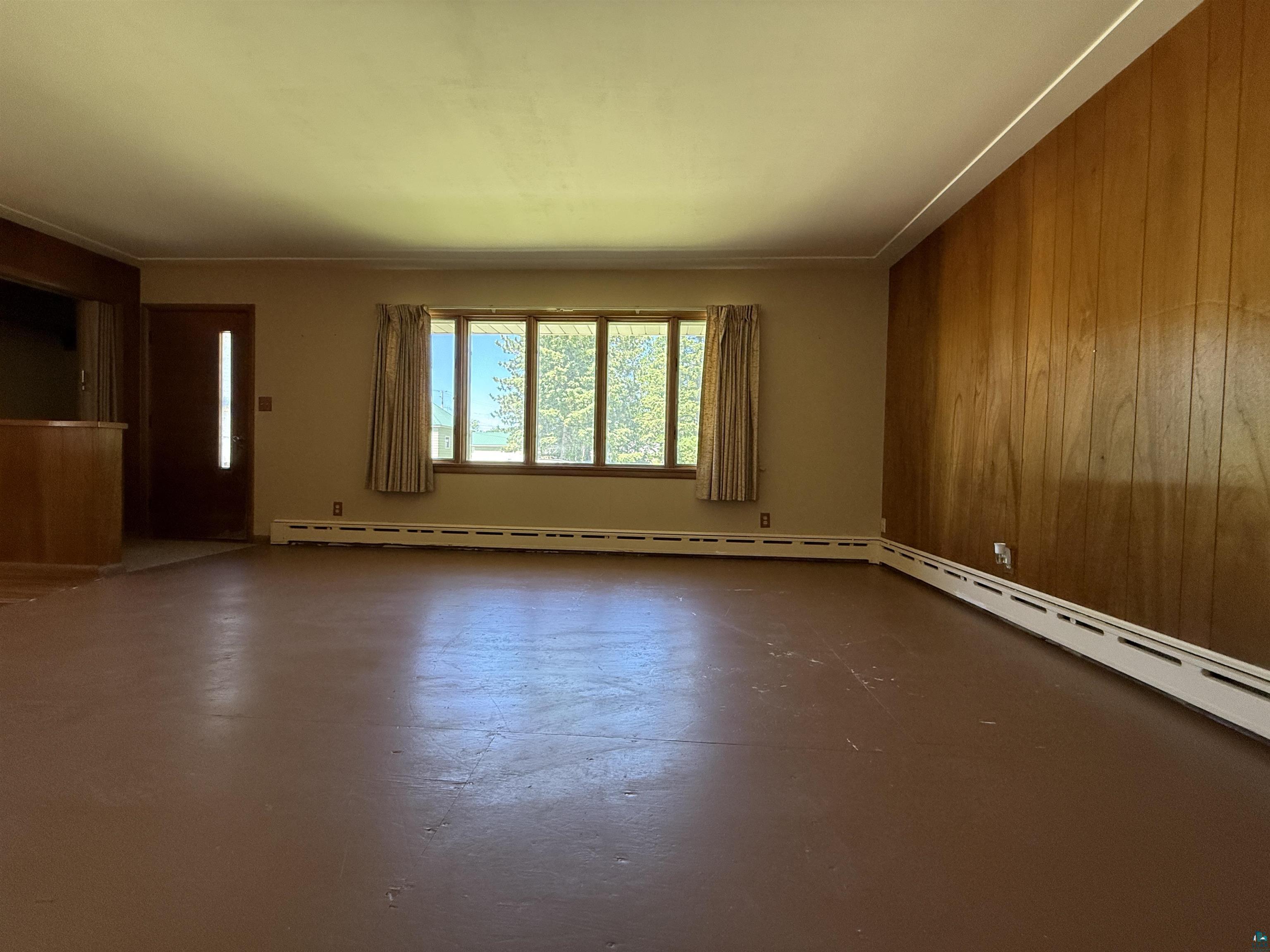 607 3rd Street Northeast Chisholm, MN 55719 - Photo 6 of 32 Spacious interior room featuring wood-finish paneling, a large multi-pane window, and baseboard heating