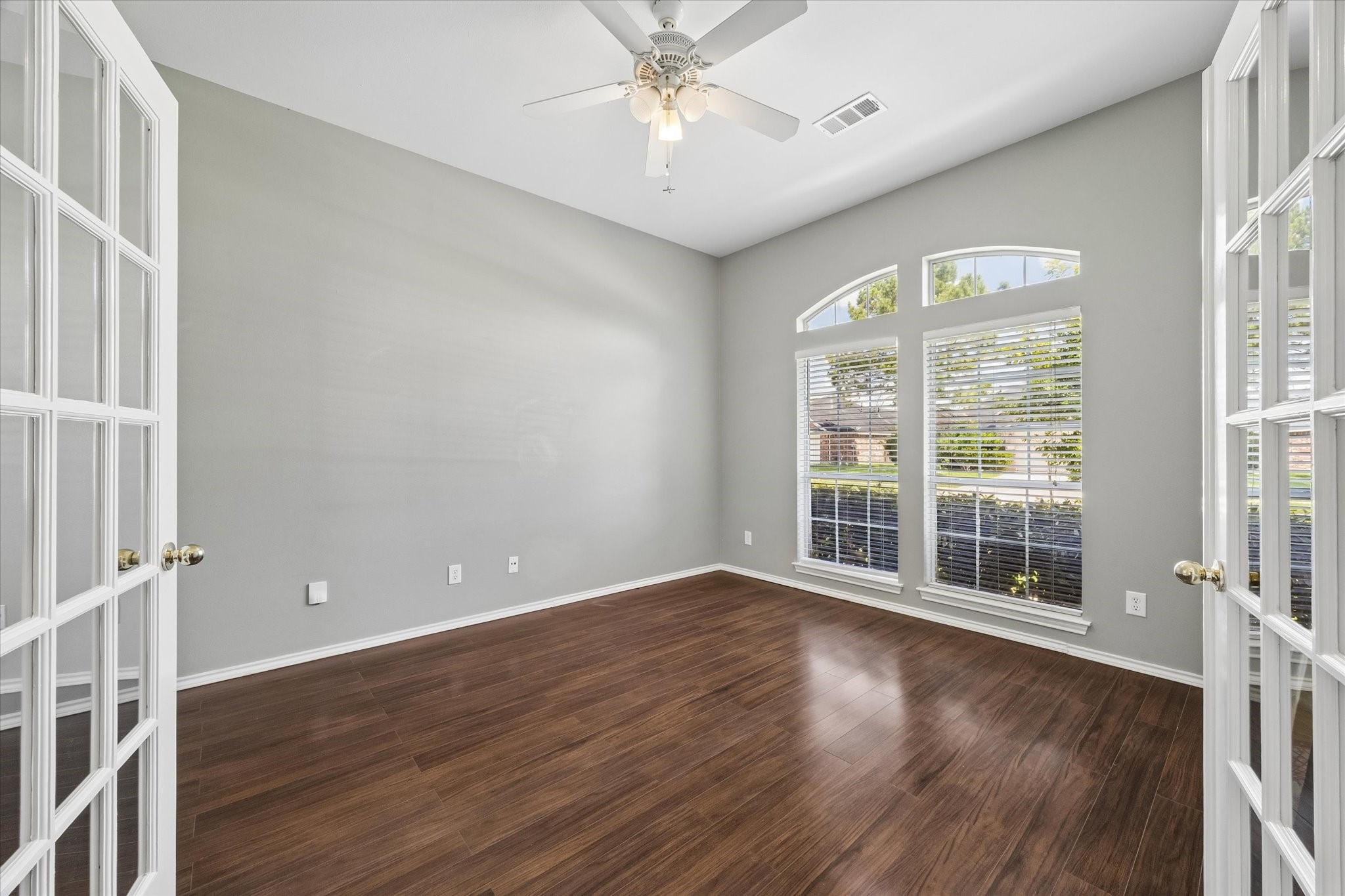 3118 Valley Court Manvel, TX 77578 - Photo 20 of 38 This bright and inviting room features hardwood floors, large arched windows with blinds, and French doors, offering plenty of natural light and a versatile space for a home office or sitting area.