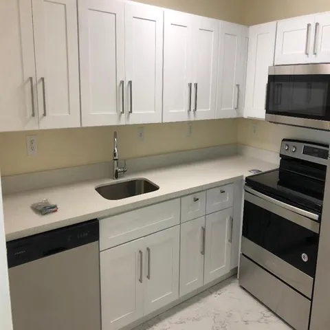 a kitchen with white cabinets and sink