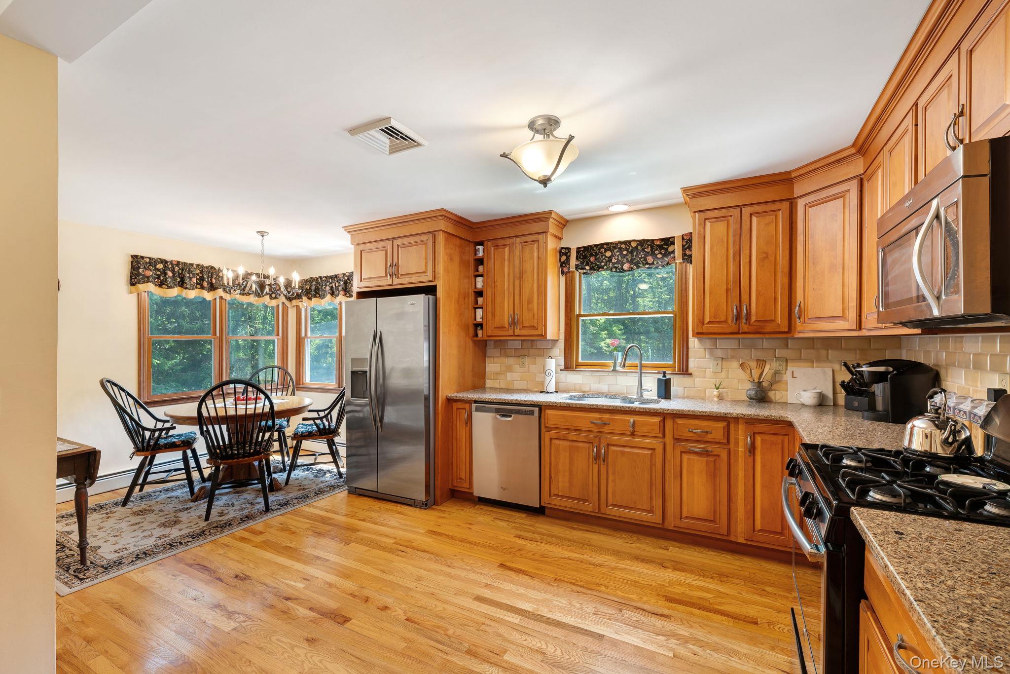 339 Kirbytown Road Middletown, NY 10940 - Photo 4 of 44 a kitchen with stainless steel appliances granite countertop a stove top oven a sink dishwasher a dining table and chairs with wooden floor