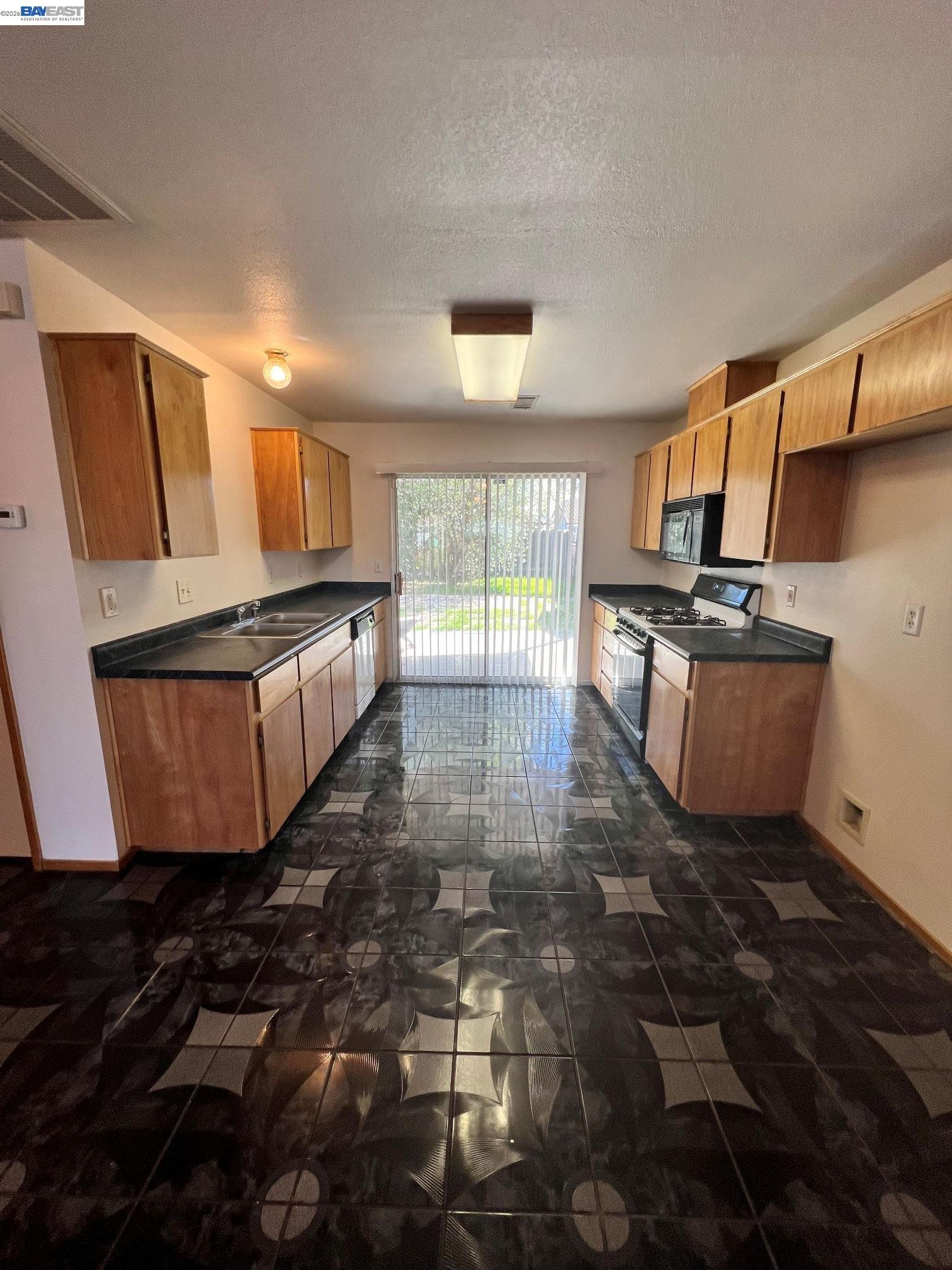192 Torvend Way Patterson, CA 95363 - Photo 9 of 29 a kitchen with granite countertop a stove a sink and a microwave