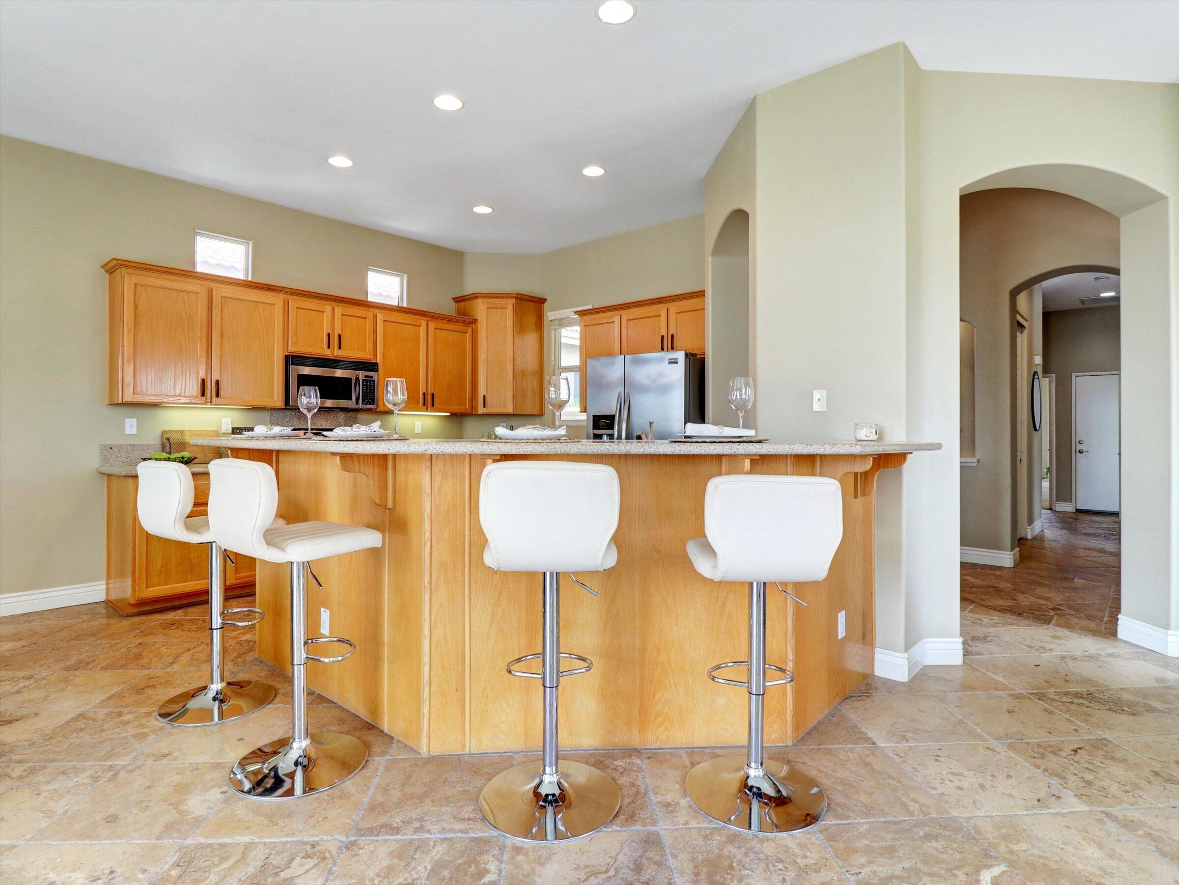 82809 Odlum Drive Indio, CA 92201 - Photo 15 of 57 a kitchen with stainless steel appliances kitchen island granite countertop dining table chairs and a refrigerator
