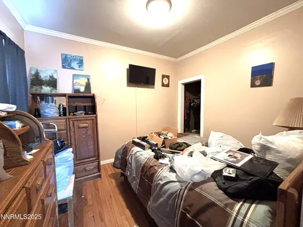 a bed sitting in a bedroom next to a flat screen tv with wooden floor