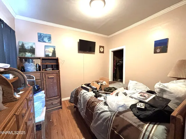 a bed sitting in a bedroom next to a flat screen tv with wooden floor