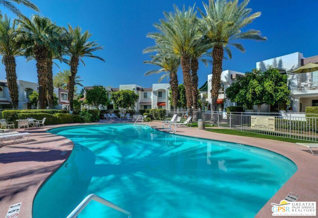 401 El Cielo Road, Unit 227 Palm Springs, CA 92262 - Photo 32 of 43 a view of a swimming pool with a lawn chairs and palm trees