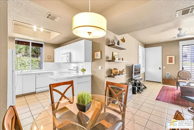 a very nice looking open dining room with kitchen island granite countertop a dining table chairs and a chandelier