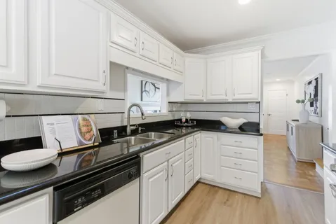 a kitchen with granite countertop white cabinets and white appliances