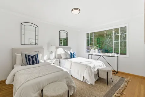 a bedroom with 2 bed and a window