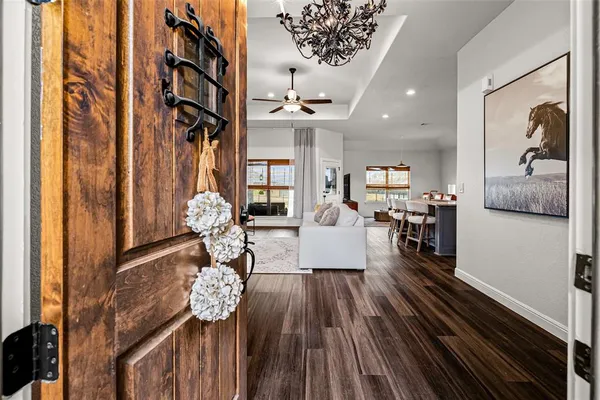 a living room with furniture a chandelier and wooden floor