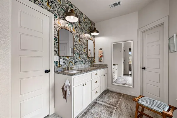 a bathroom with a granite countertop sink a mirror and a shower
