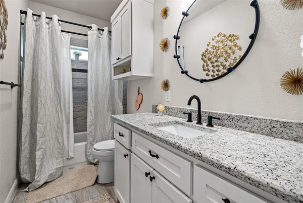 a bathroom with a granite countertop sink a toilet and a mirror
