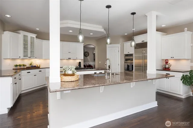 a large kitchen with kitchen island a stove a sink a center island and wooden floor