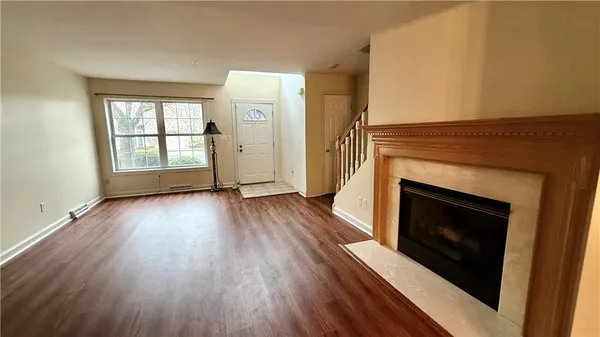an empty room with wooden floor fireplace and windows