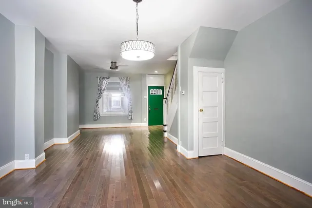 a view of an empty room with wooden floor and window