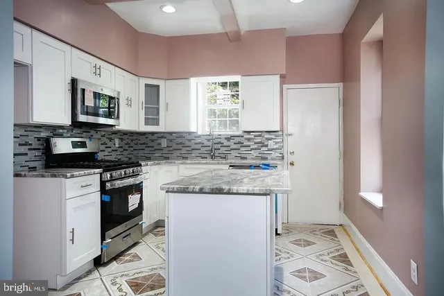 a kitchen with stainless steel appliances granite countertop a stove a sink and a microwave
