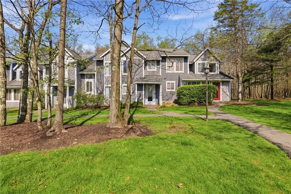 a view of a white house next to a yard with big trees