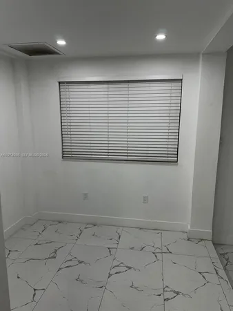 an empty room with white walls and mirror