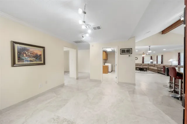 a view of an empty room and a kitchen