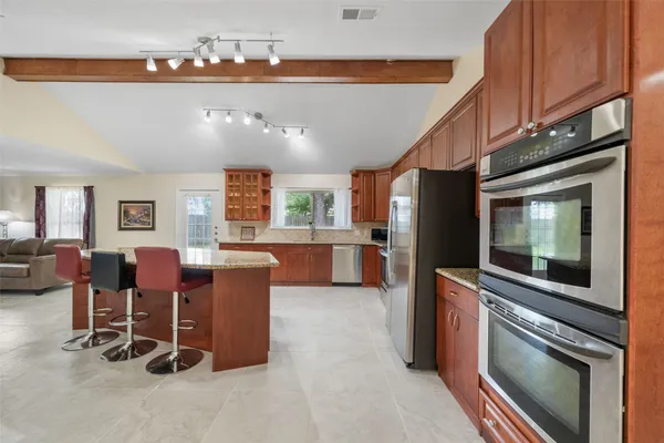 a kitchen with stainless steel appliances kitchen island granite countertop furniture and a refrigerator