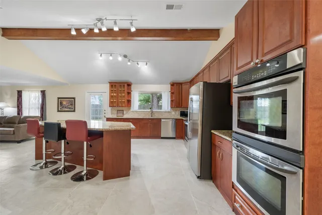 a kitchen with stainless steel appliances kitchen island granite countertop furniture and a refrigerator