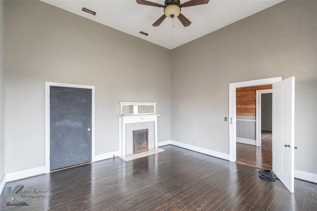 141 East 3rd Street Baird, TX 79504 - Photo 9 of 33 an empty room with wooden floor a ceiling fan and windows