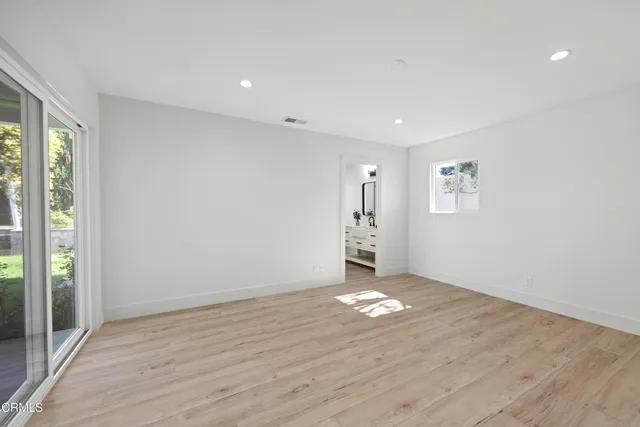 a view of an empty room with window and wooden floor