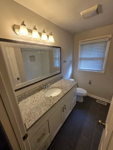 a bathroom with a granite countertop sink a mirror and shower