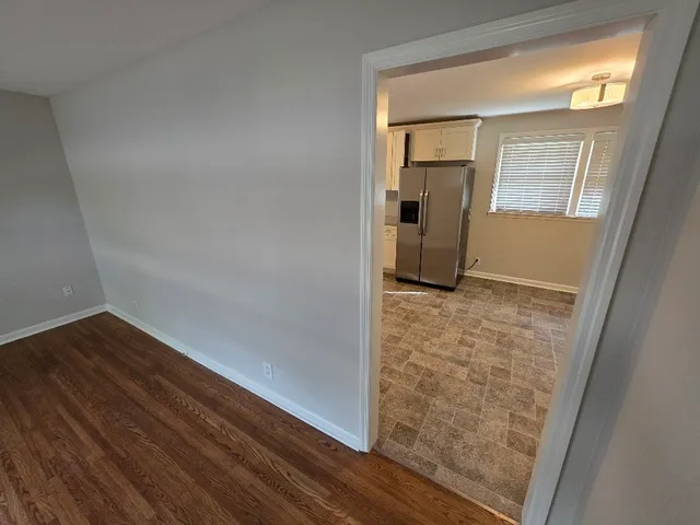 a view of a hallway with wooden floor and a livingroom