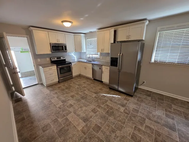a kitchen with granite countertop a refrigerator and a stove top oven