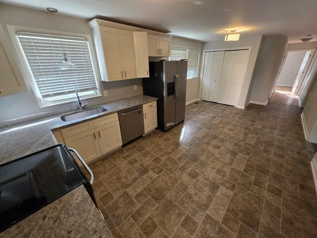 a kitchen with granite countertop a refrigerator and a sink