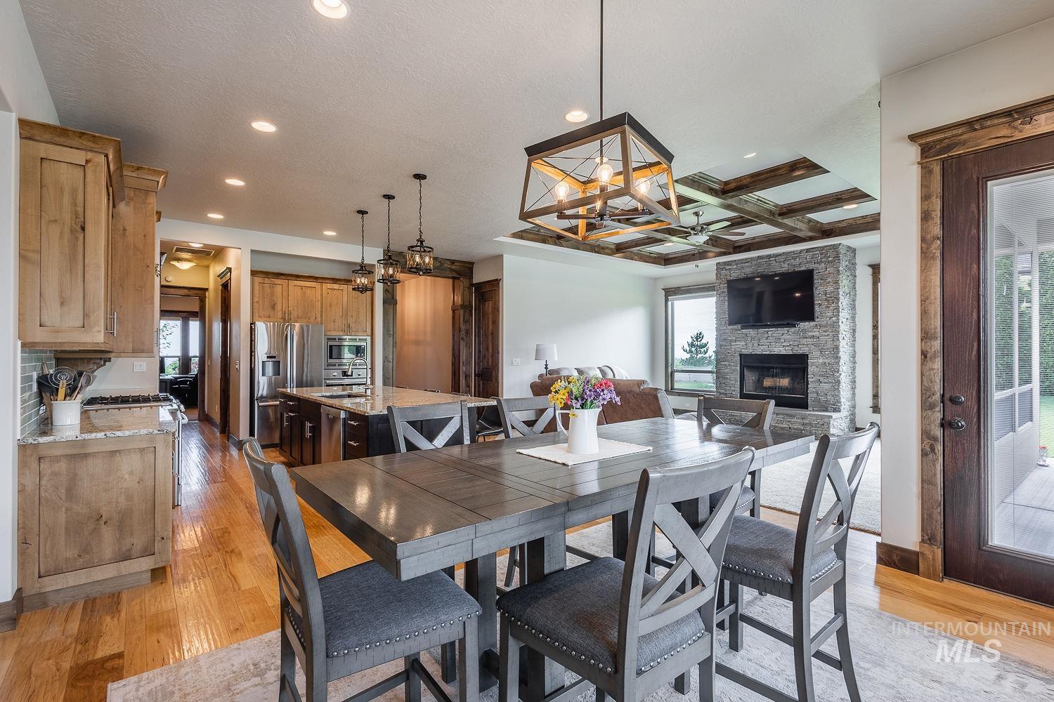 8077 Star Pass Ridge Road Nampa, ID 83686 - Photo 15 of 37 Living area featuring a stone-clad fireplace with hearth, a coffered ceiling with wood beams, and recessed lighting