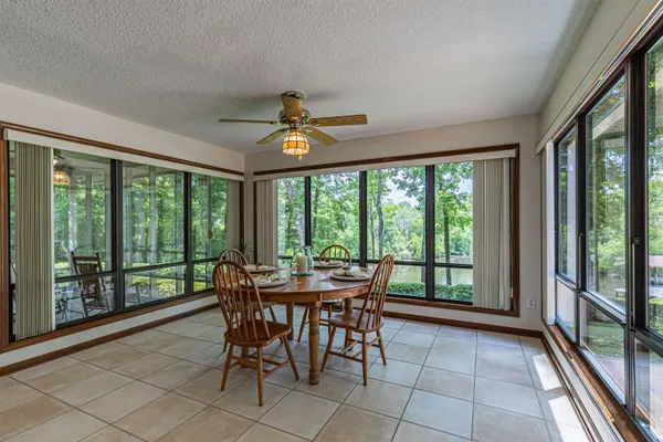 a kitchen with a stove a sink a dining table and chairs with a large window