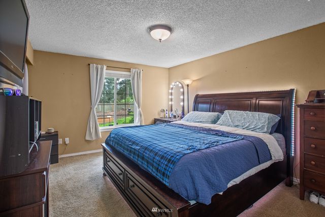 a bedroom with a bed and a flat tv screen on dresser