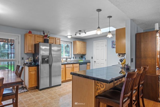 a kitchen with stainless steel appliances a dining table chairs and refrigerator