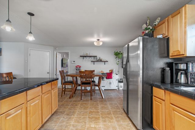 a kitchen with stainless steel appliances granite countertop a refrigerator a sink dishwasher a dining table and chairs with wooden floor