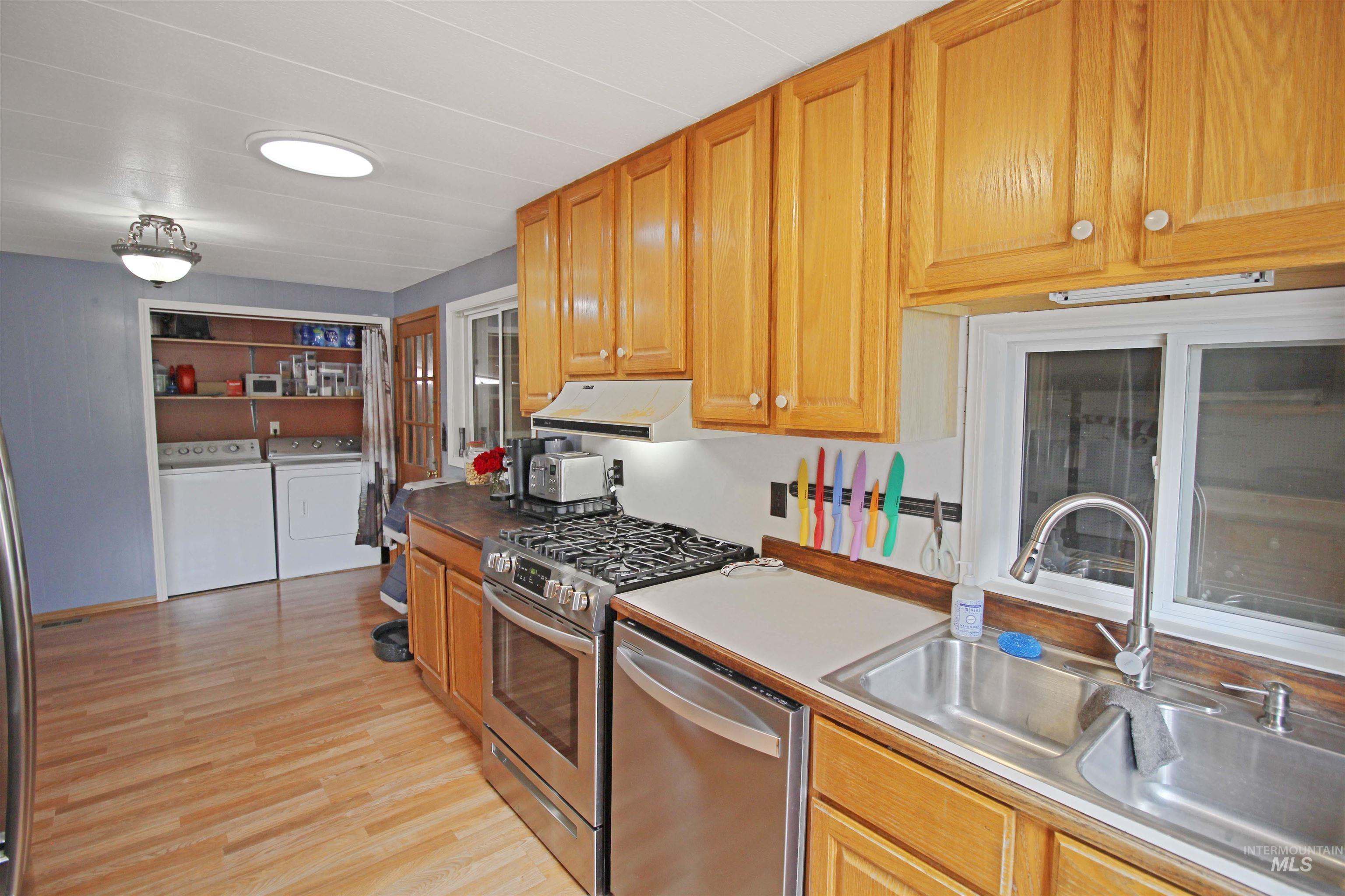 1265 Pioneer Road Weiser, ID 83672 - Photo 9 of 29 Kitchen featuring wood-finish flooring, natural wood cabinetry, stainless steel appliances, a double basin sink, and a skylight