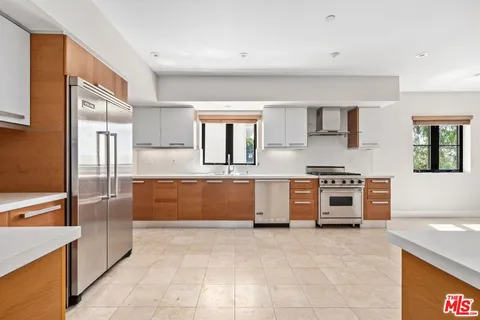 a large kitchen with stainless steel appliances a stove a sink and a refrigerator