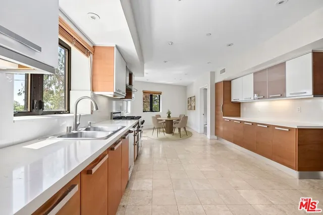 a large kitchen with kitchen island a large window a sink and stainless steel appliances